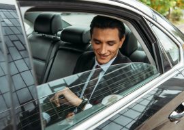 Smiling businessman looking at wristwatch in taxi